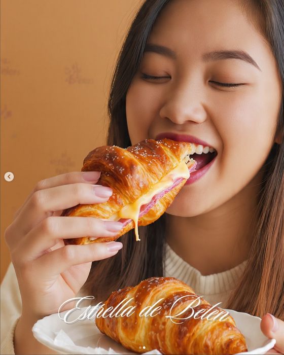 Chica mordiendo una medialuna rellena de jamón y queso
