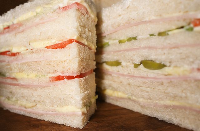 Sándwiches de miga triple capa cortados en triángulos, con jamón, queso y tomate